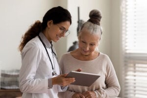 Doctor showing a cataract surgery preparation guide on a tablet to a senior patient