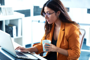 Woman at a laptop noticing persistent eyelid twitching—know the red flags that need an eye exam.”