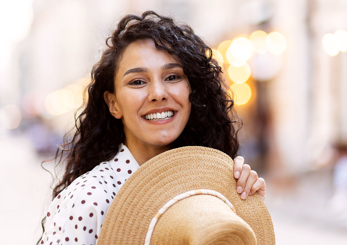 Smiling woman holding a sun hat—featured image for why does my vision change after 40