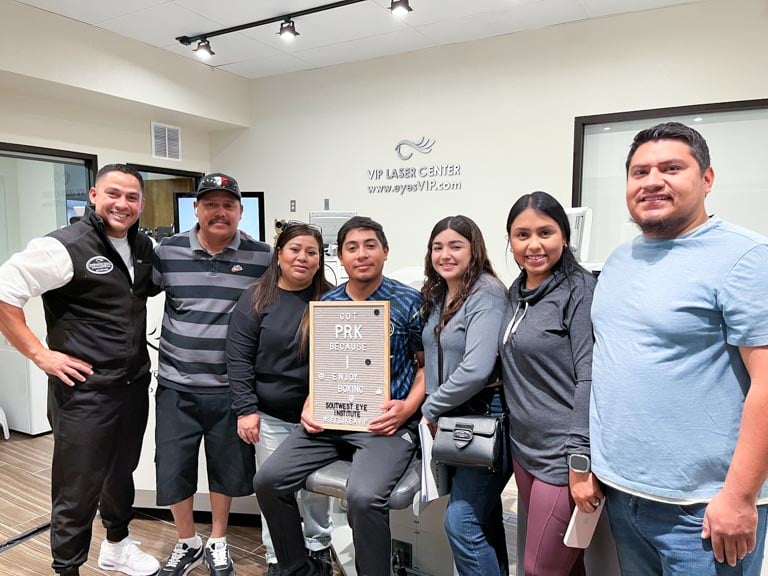 PRK patient holding a sign at Southwest Eye Institute in El Paso, surrounded by family after successful laser vision correction.