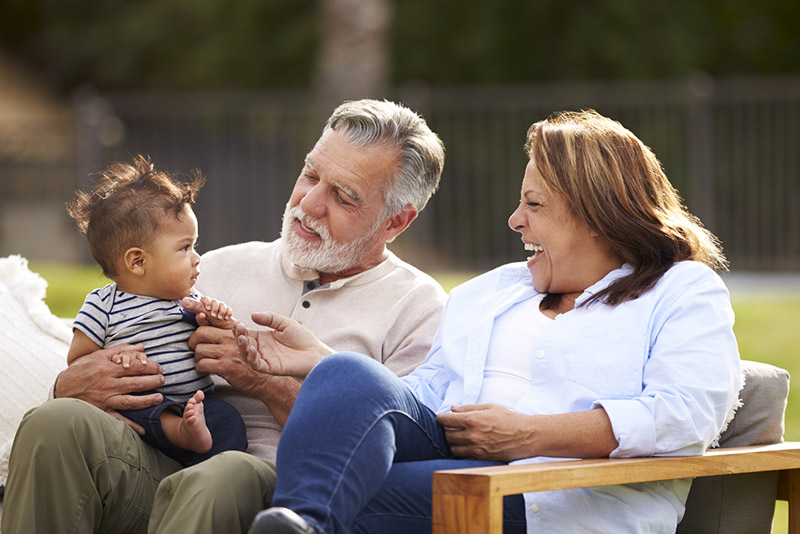 Couple holding their grandbaby, representing preserved vision and long-term eye health after corneal cross-linking treatment.