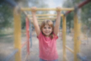 Point-of-view image simulating cloudy vision after cataract surgery, showing a child playing on a jungle gym where most of the scene looks hazy and foggy, with one small central area slightly clearer to represent how vision can suddenly blur and distort, created for Southwest Eye Institute.