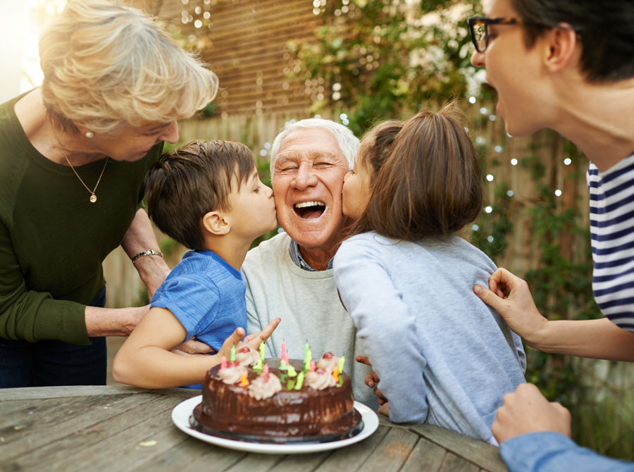 Benefits of cataract surgery shown through a grandfather clearly seeing and enjoying a joyful birthday moment with his family and grandchildren.