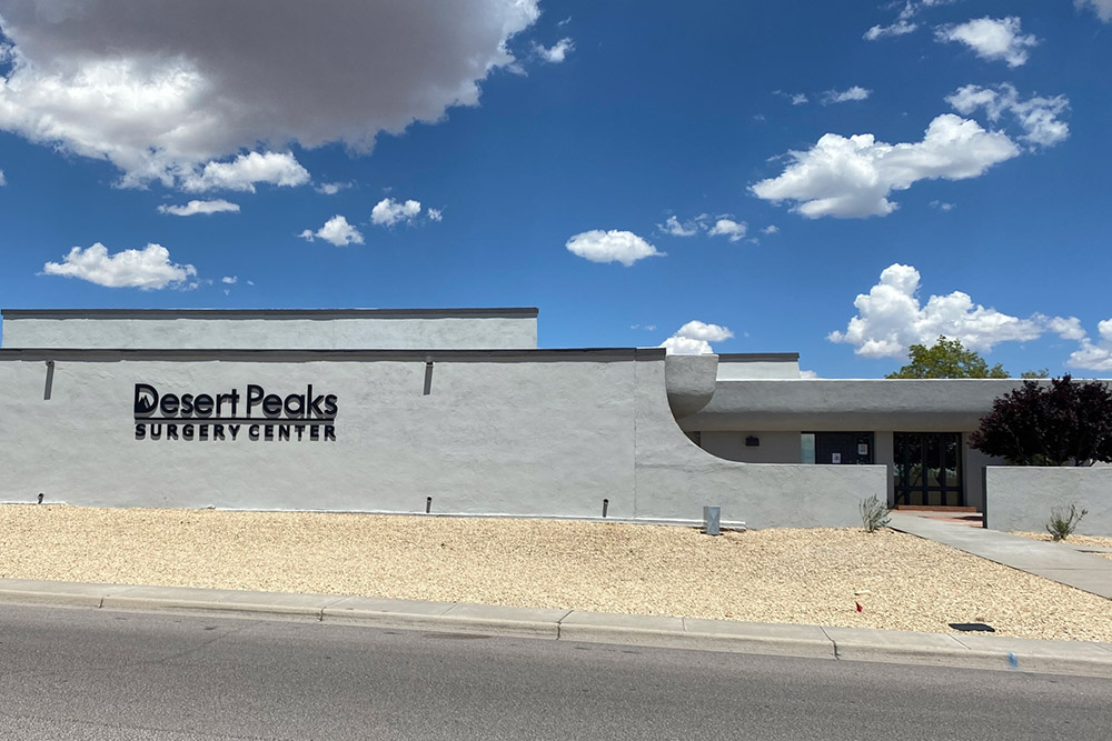 Desert Peaks Surgery Center exterior with signage on a light stucco building under a blue sky with clouds.